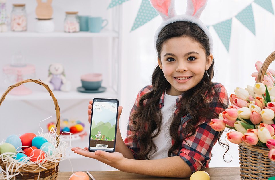 Mädchen mit Smartphone und Bunny Runner Browser-Game zu Ostern